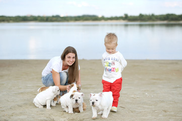 mother with the son on the river bank play with puppies of breed