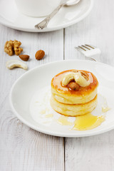 Fototapeta na wymiar Fritters of cottage cheese with honey and nuts on a white plate