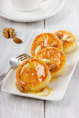 Fritters of cottage cheese with honey and nuts on a white plate