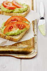 Avocado cream with toasts and tomatoes on a rustic surface