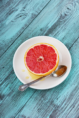 Grapefruit with honey on a white plate on a vintage background