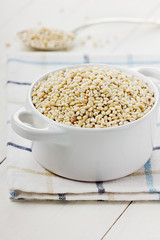 Pearl barley in a white ceramic bowl on a wooden surface
