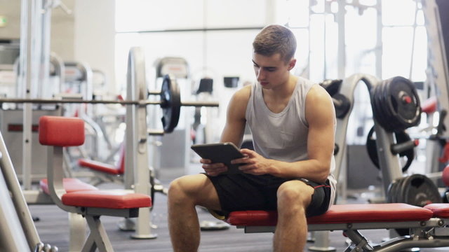 young man with tablet pc computer in gym