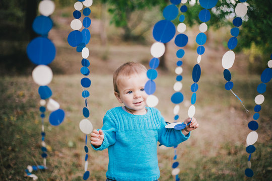 Little fashion boy in a forest wearing blue sweater and jeanse