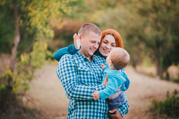 Fototapeta premium Happy family in blue stylish clothes walking in autumn forest