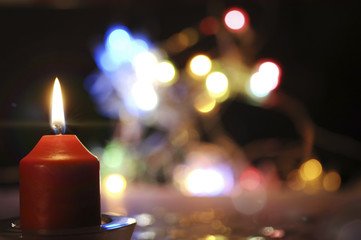 brennende Kerze und bunte Lichter
