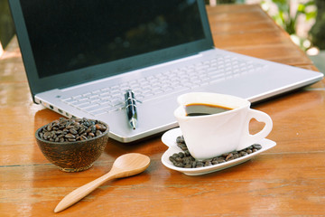 Cup of coffee and laptop on wooden table.