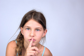 Young girl with finger on lips shushing