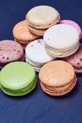 Colorful macaroons on black slate, close up view