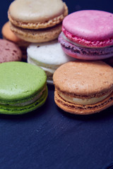 Colorful macaroons on black slate, close up view