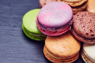Colorful macaroons on black slate, close up view