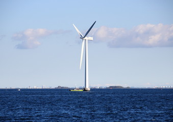Ocean windmill in rough sea with inspection ship