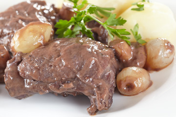 Chicken in red wine with onions, mushrooms and bacon