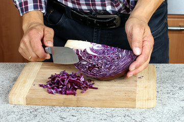 Mann bearbeitet rohen Rotkohl mit Messer, kochen