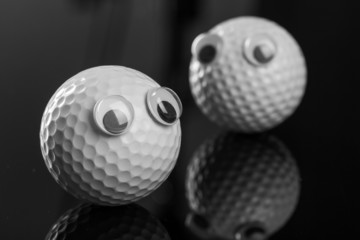 Two golf balls with plastic eyes