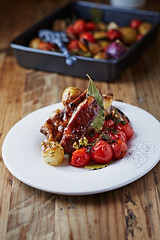 Pork ribs with baked potatoes and cherry tomatoes on a plate