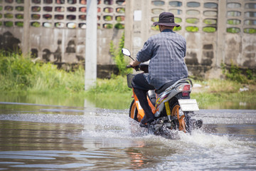 Fototapeta premium Splash by a motorcycle as it goes through flood water