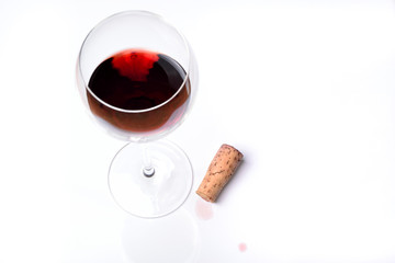 A glass of red wine with cork on a white background