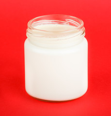 jar with yogurt isolated on red background