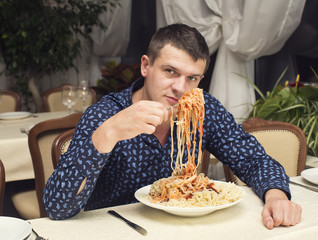 man eating a large portion of pasta in a restaurant