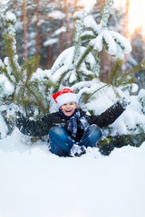 Fototapeta na wymiar Happy boy in a cap of Santa Claus in the winter forest.