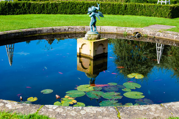 English Landscape garden in Summertime with fishpond and statue