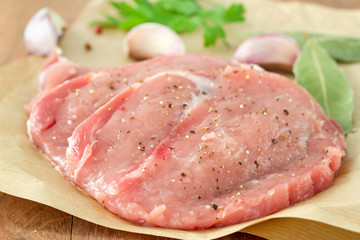 pork with garlic and parsley on paper on brown background