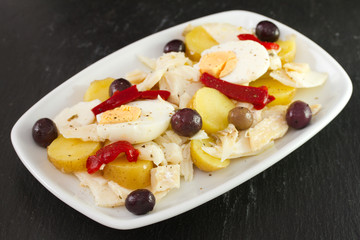 cod fish salad with olives in white dish