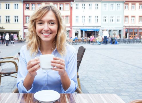 Frau mit blonden Locken bei einem Kaffee im Freien