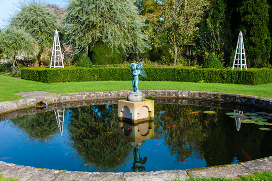 English Landscape garden in Summertime with fishpond and statue