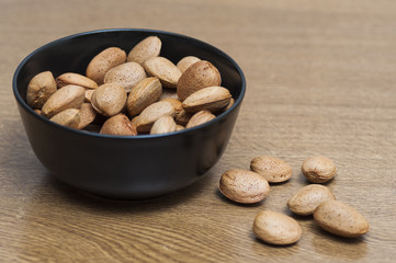 Almonds on a black bowl on wooden background