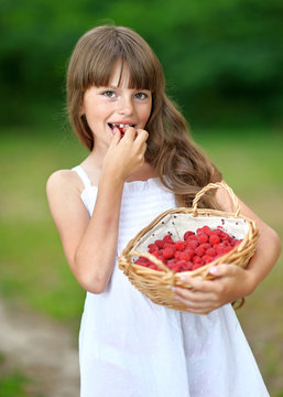 portrait of a beautiful little girl with raspberries