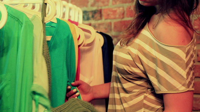 Woman looking on green blouse in the boutique 