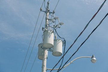 electrical transformers hanging on light  pole against blue sky