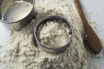 pastry cutters and flour on white wooden board