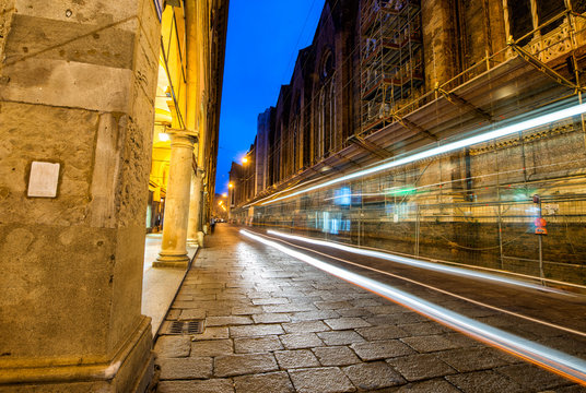 Illuminated street of Bologna at night with bus light trails