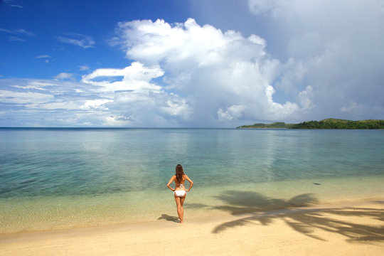 Young woman in bikini standing on a tropical beach, Nananu-i-Ra
