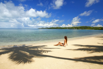 Young woman in bikini sitting on a tropical beach, Nananu-i-Ra i