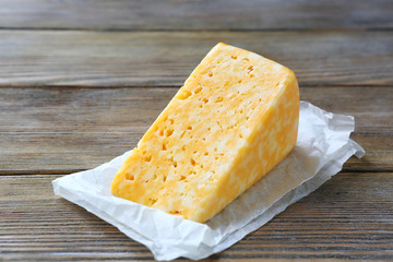 chunk of yellow cheese on a wooden background