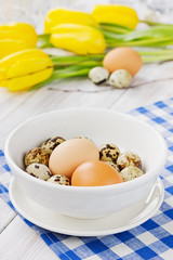 Easter table with chicken and quail eggs, yellow tulips