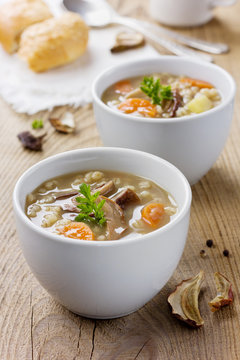 Mushroom soup with barley and vegetables in white plate