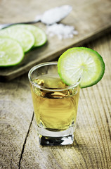 Tequila shot with lime and salt on rustic wooden background