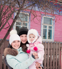 Beautiful family in warm clothes standing of his house in winter
