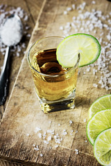 Tequila shot with lime and salt on vintage wooden background
