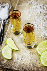 Tequila with lime and salt on vintage wooden background