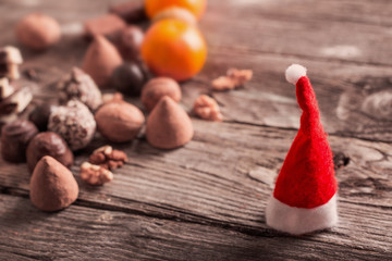 Christmas hat with chocolate and orange on old wooden table