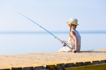 Girl in a dress and a hat with a fishing rod