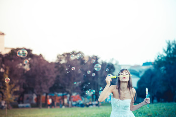 beautiful young woman with white dress blowing bubble
