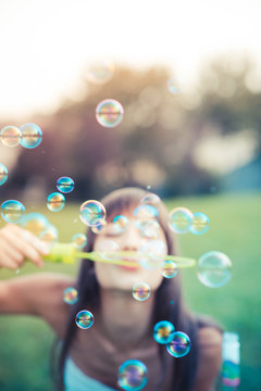 beautiful young woman with white dress blowing bubble
