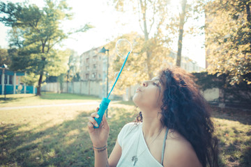 young beautiful moroccan curly woman blowing bubbles